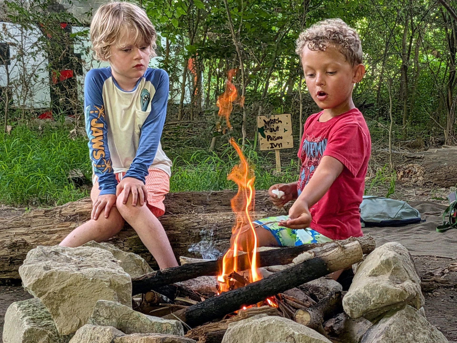 Two children gathered around a campfire during a forest co-op day